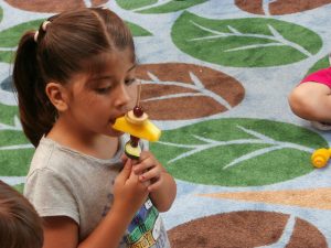 Criança comendo espeto de frutas